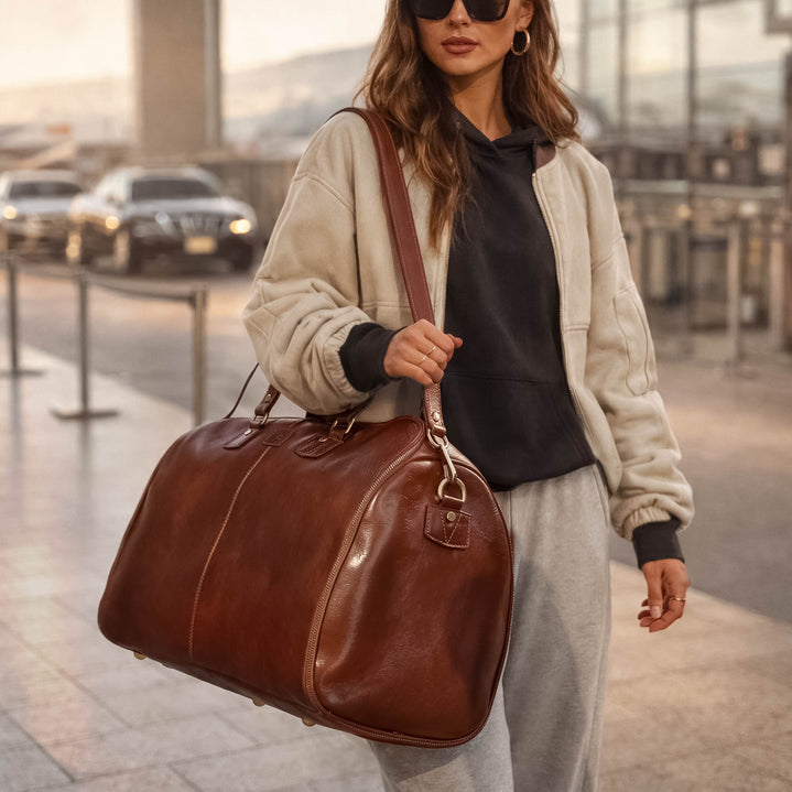 Von Baer Grand large full-grain leather garment bag for women in brown with female model near the airport, luxury travel bag for professionals.