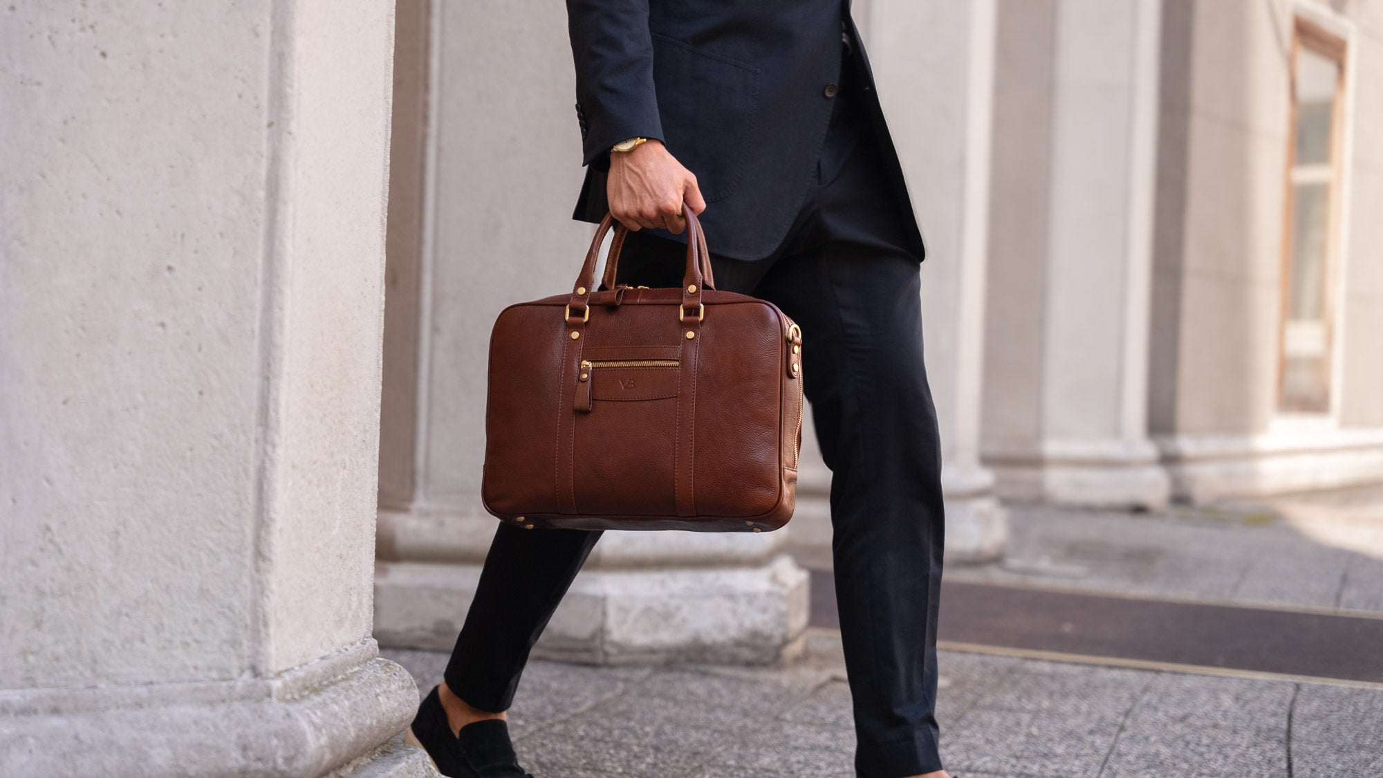 Handsome man in a suit holding a brown Von Baer luxury business leather laptop bag