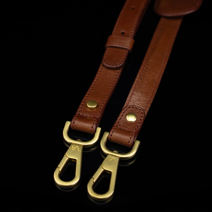 A close-up of the hooks on a Von Baer leather shoulder bag strap, showing the Von Baer logo.