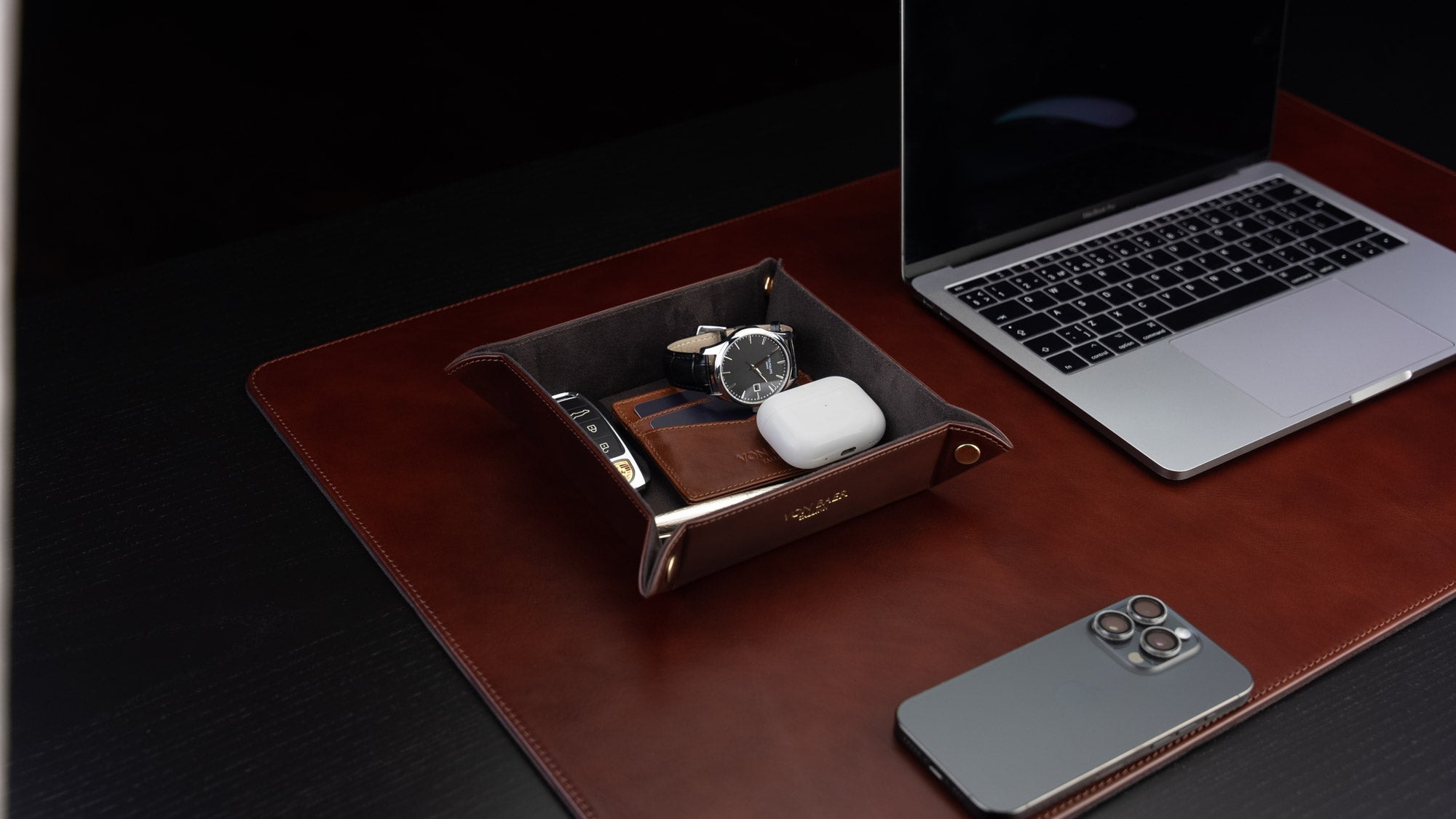 Von Baer Majestic luxury Italian leather tray desk organizer, catch-all in brown, placed on a leather desk pad and filled with items, shown in a slider.