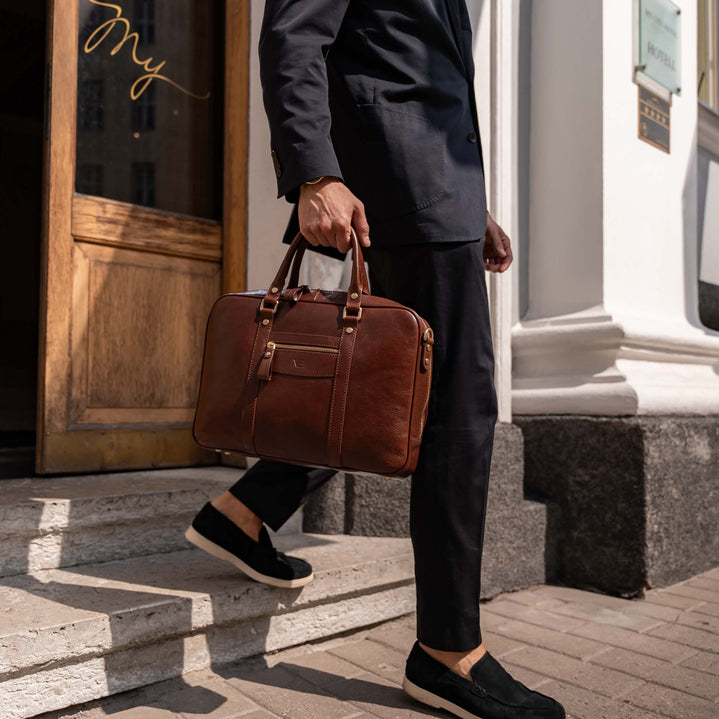 Man in a suit holding a brown Von Baer luxury leather laptop bag