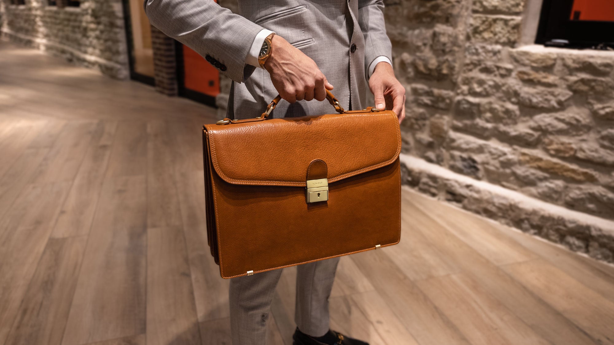 A lawyer is holding a tan Von Baer No.1 luxury Italian leather bag.