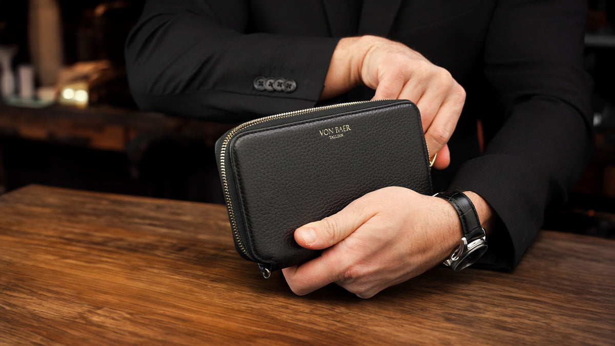 Von Baer origin luxury RFID men’s leather wallet in black held by a male model in a café shop, premium wallet for professionals.