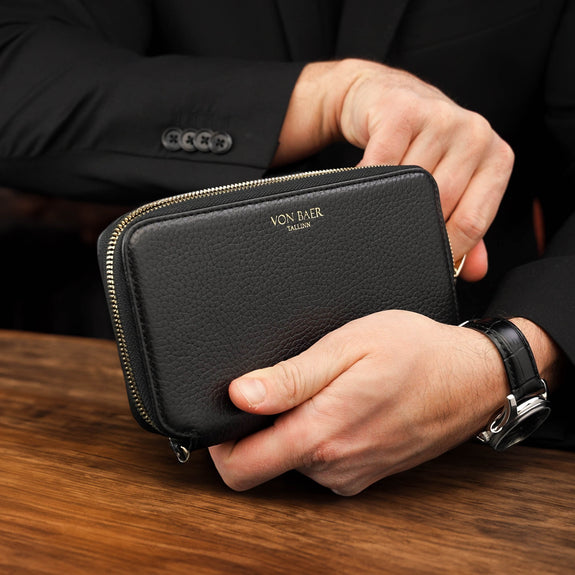 Von Baer origin luxury RFID men’s leather wallet in black held by a male model in a cafe, premium wallet for cards and cash.