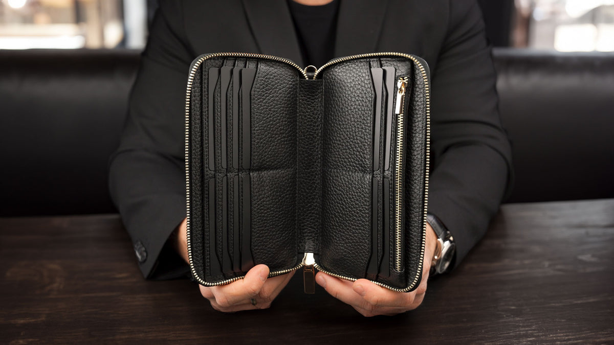 Von Baer origin luxury RFID men’s leather wallet in black held by a male model showing interior pockets for cards and cash.