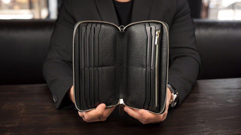Von Baer origin luxury RFID men’s leather wallet in black held by a male model showing interior pockets for cards and cash.