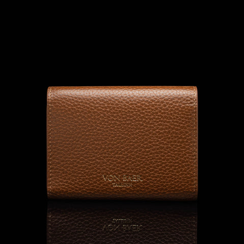 Von Baer Reverie compact cognac pebbled leather wallet for women, shown from the back with debossed Von Baer Tallinn branding, centered against a black background with a subtle reflection below