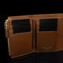Von Baer Reverie luxury small cognac pebbled leather wallet for women, open to showcase eight card slots, black cards, a gold-tone zipper pull, and the debossed brand logo on the interior against a black background