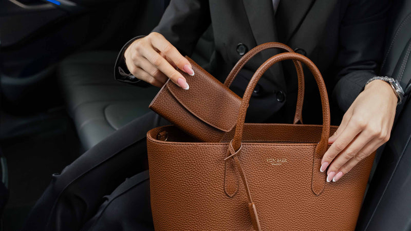 Von Baer Elise cognac tan women's full-grain leather wallet shown inside an open Isabella Grande large leather crossbody bag, held by a woman in a black blazer to display interior compartments.