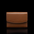 Von Baer Reverie small cognac tan pebbled leather wallet for women with a curved flap closure, shown centered in a front view against a solid black background with a subtle reflection.