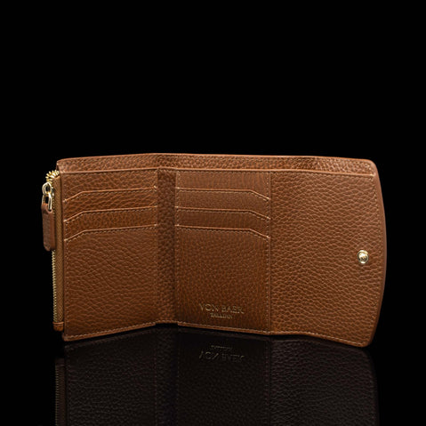 Von Baer Reverie cognac pebbled leather women's wallet, shown open against a black background to highlight multiple card slots, a zippered pocket, and elegant gold-tone hardware