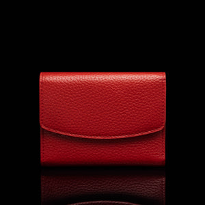Von Baer Reverie small deep red full-grain pebbled leather wallet for women with a curved envelope-style flap, shown centered in a front view against a solid black background with a subtle reflection.