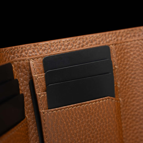Von Baer Reverie luxury cognac pebbled compact leather wallet for women, shown in close-up with black cards inserted into the interior card slots against a dark background