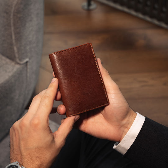 Von Baer Tallinn Grant leather card case in brown held by a male model in a luxury hotel setting