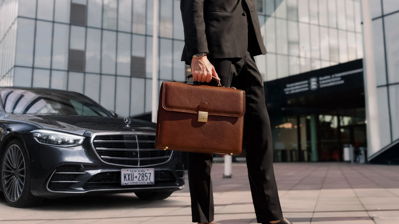 Von Baer diplomat men's traditional brown leather briefcase, held by a man in a suit in front of a modern office building with a Mercedes S-Class parked nearby