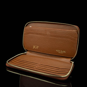 Brown leather wallet with gold zipper on a black background