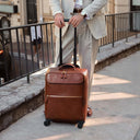 vb Voyager full-grain leather luxury trolley carry-on bag with wheels, shown with a male model in a cream suit to highlight style and travel functionality