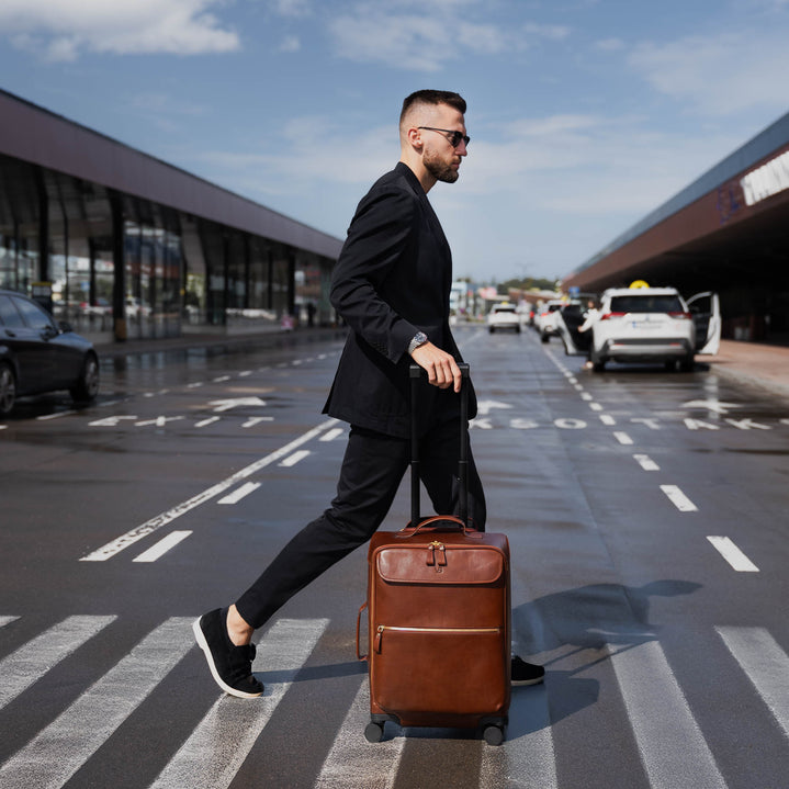Von Baer Voyager luxury carry-on trolley bag in airport carried by stylish man on crosswalk