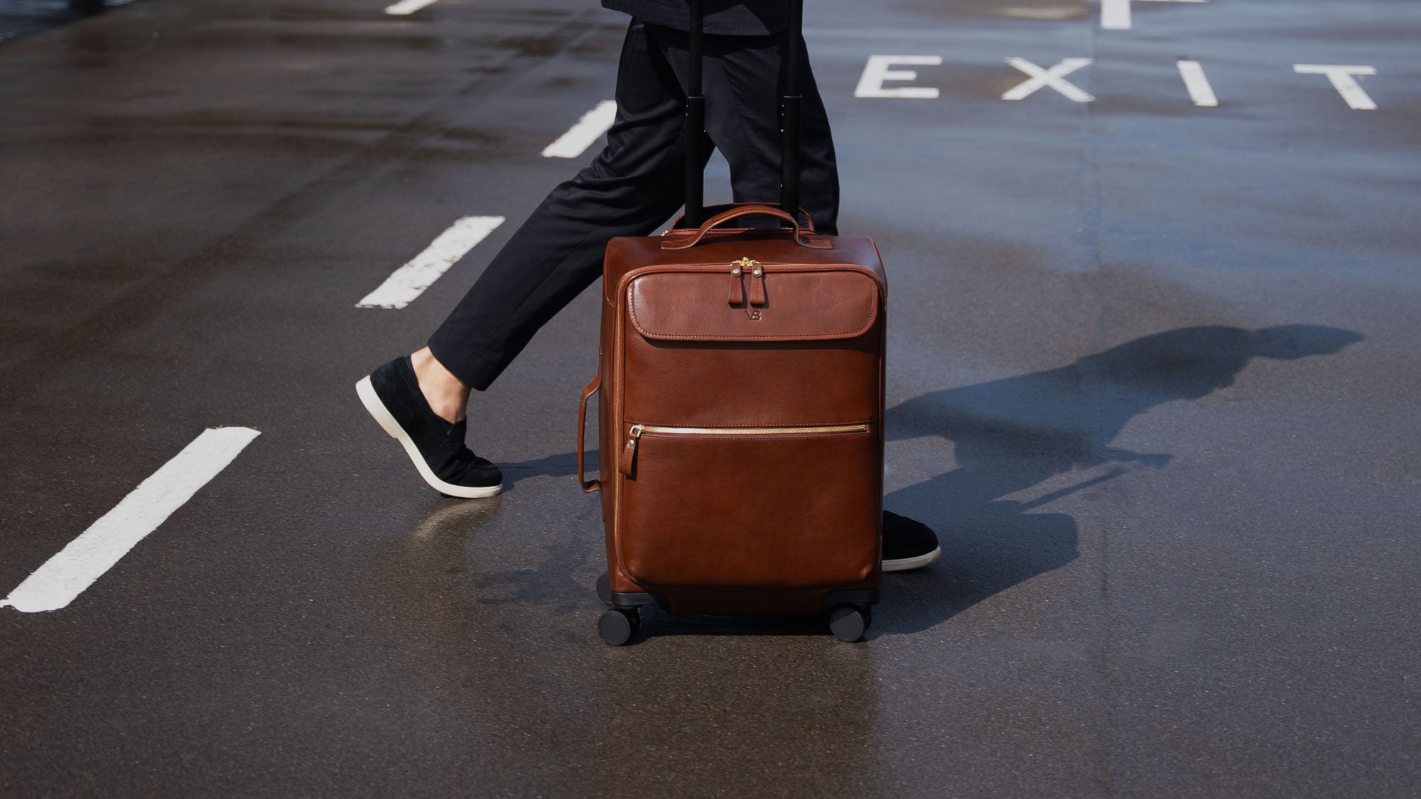 Von Baer Voyager luxury carry on trolley bag carried by a man crossing the road at an airport