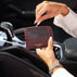 A person holding a luxurious burgundy pebbled leather card holder wallet with gold lettering that reads 'VON BAER' inside a car interior.