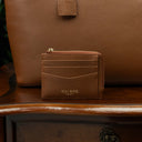 Zipped full grain leather card case with RFID protection on a vintage table with a tote bag in the background