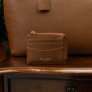 Zipped full grain leather card case with RFID protection on a vintage table with a tote bag in the background